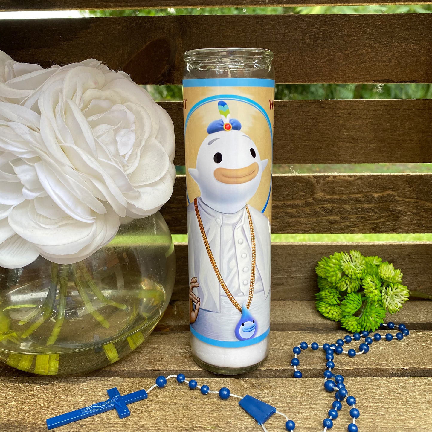 a white flower and a blue and gold necklace next to a white flower in a