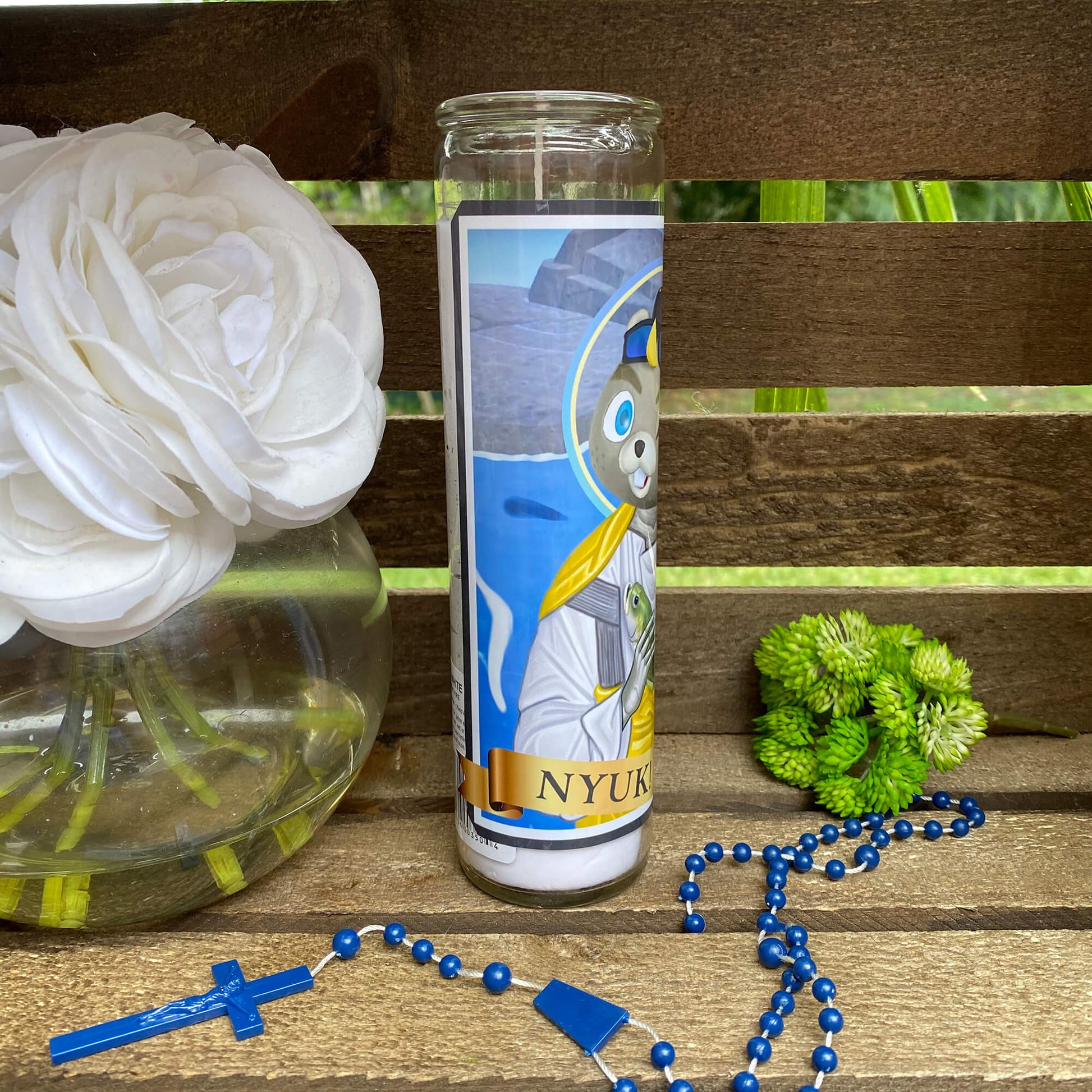 a rosary, a vase with flowers, and a candle on a bench
