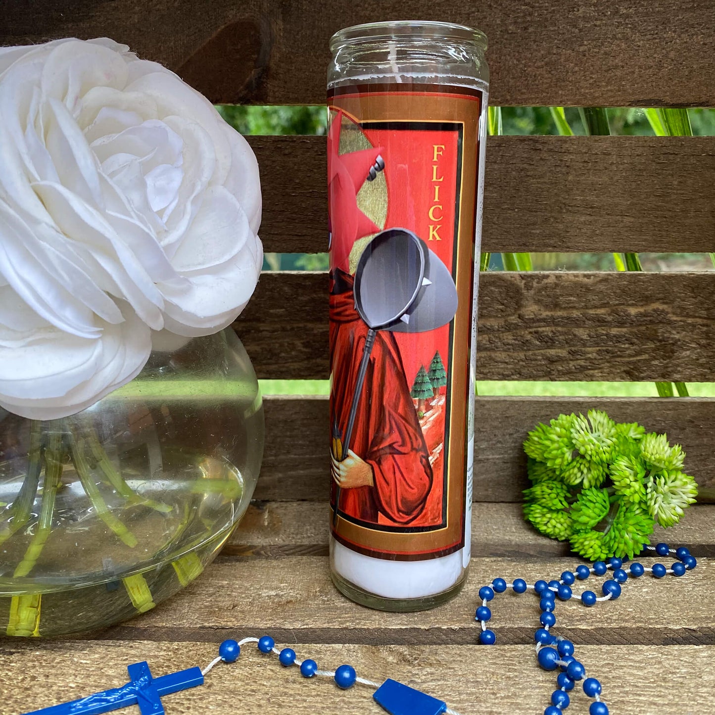 a candle with a spoon on a table next to a flower