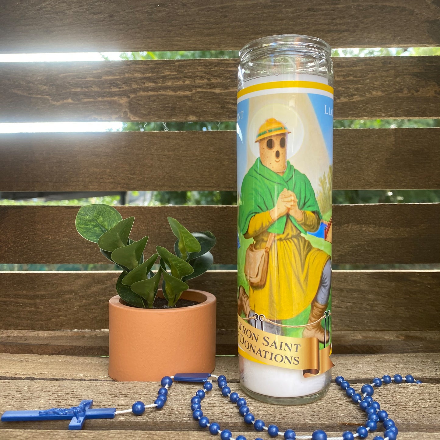 a candle with a picture of jesus on it next to a plant