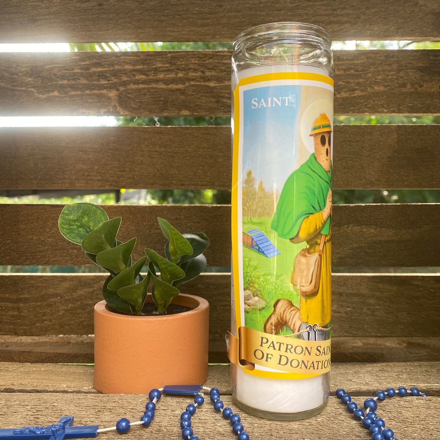 a candle with a picture of a man on it next to a potted plant