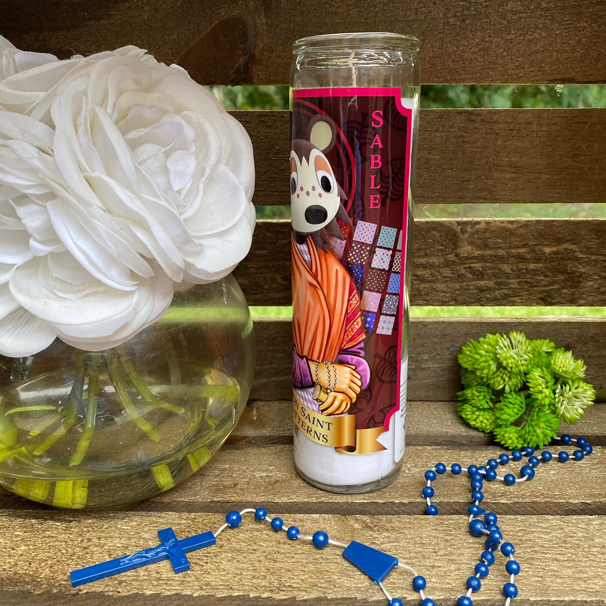 a vase of flowers and a rosary on a bench