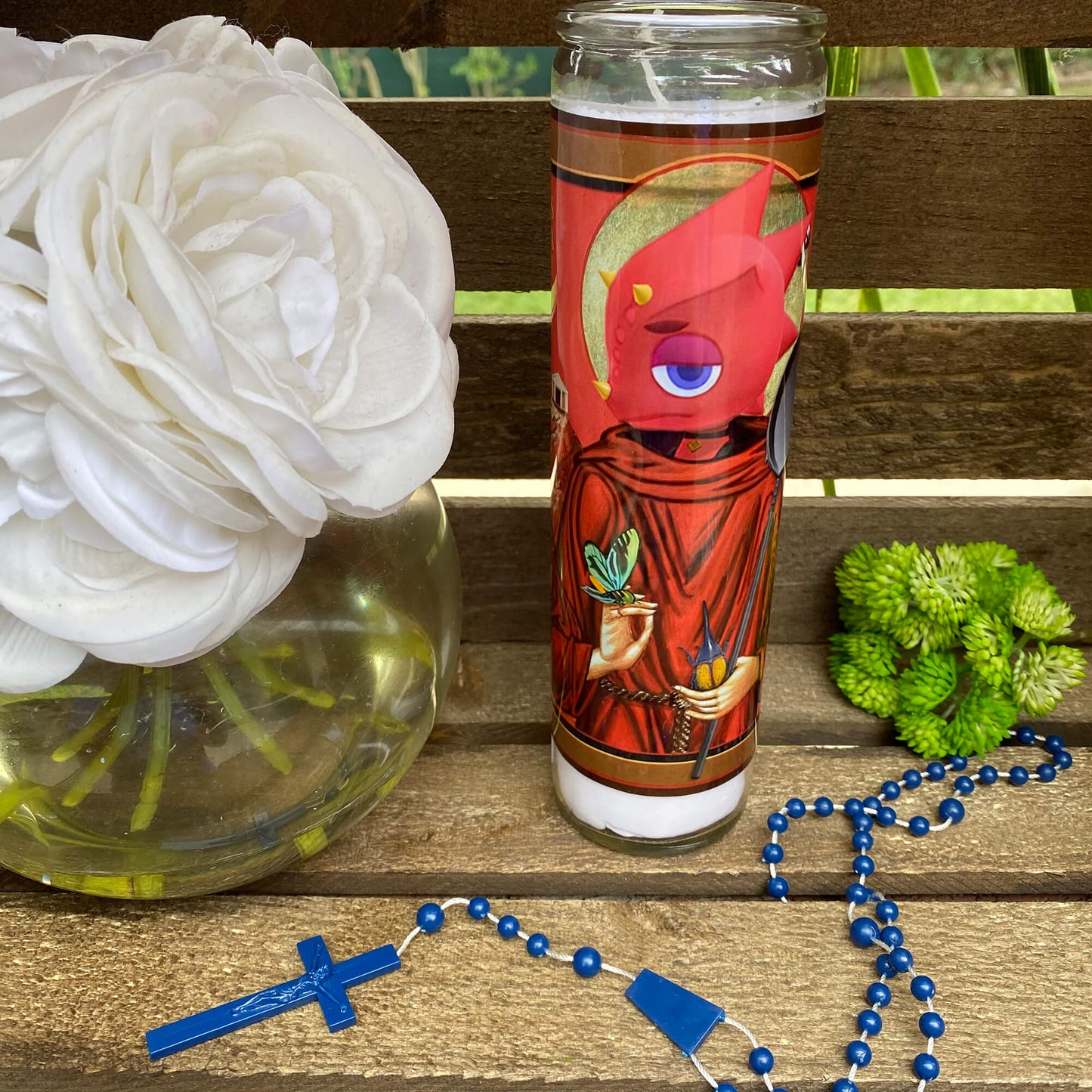a cup with a rosary and a flower on a bench