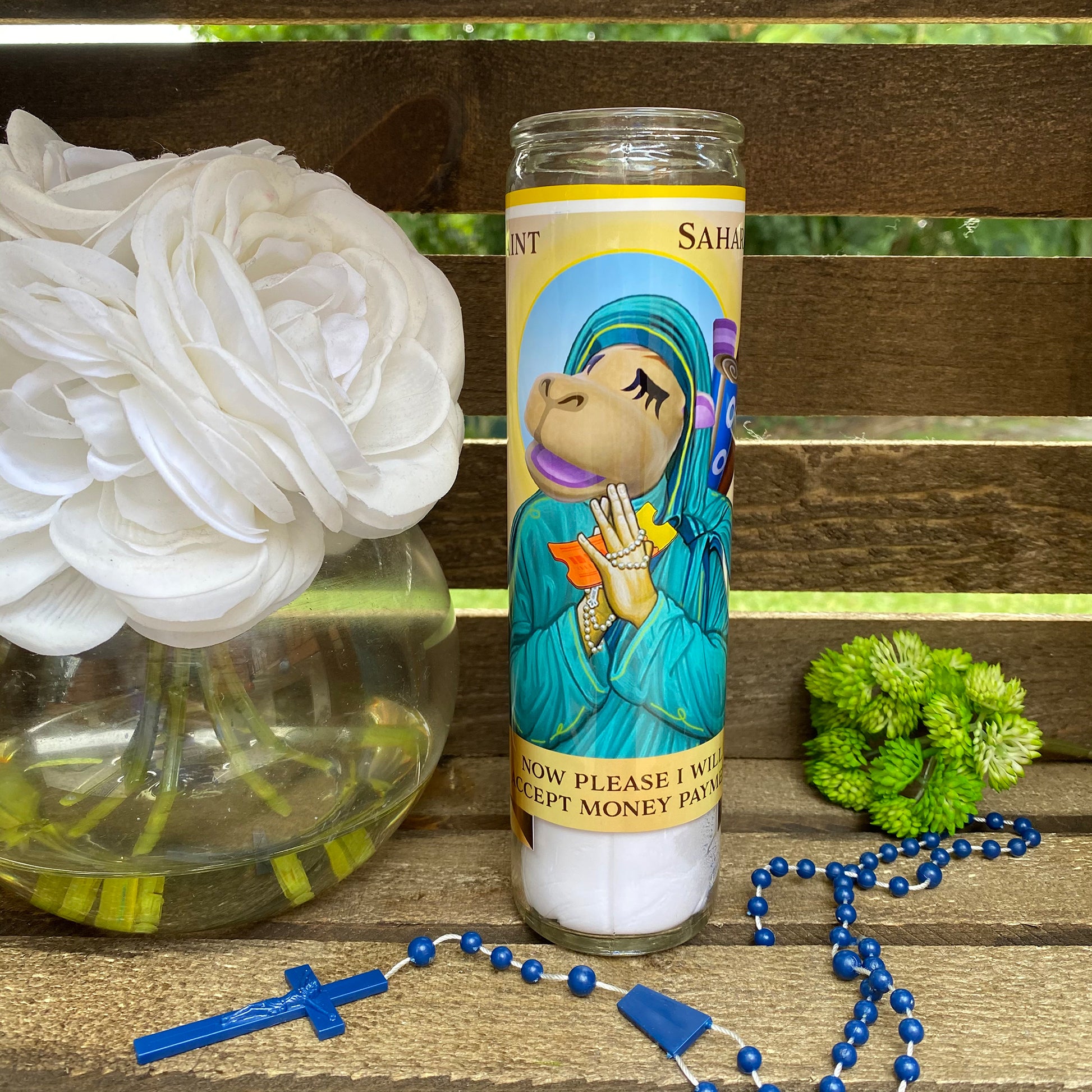 a candle with a rosary and a flower on a bench