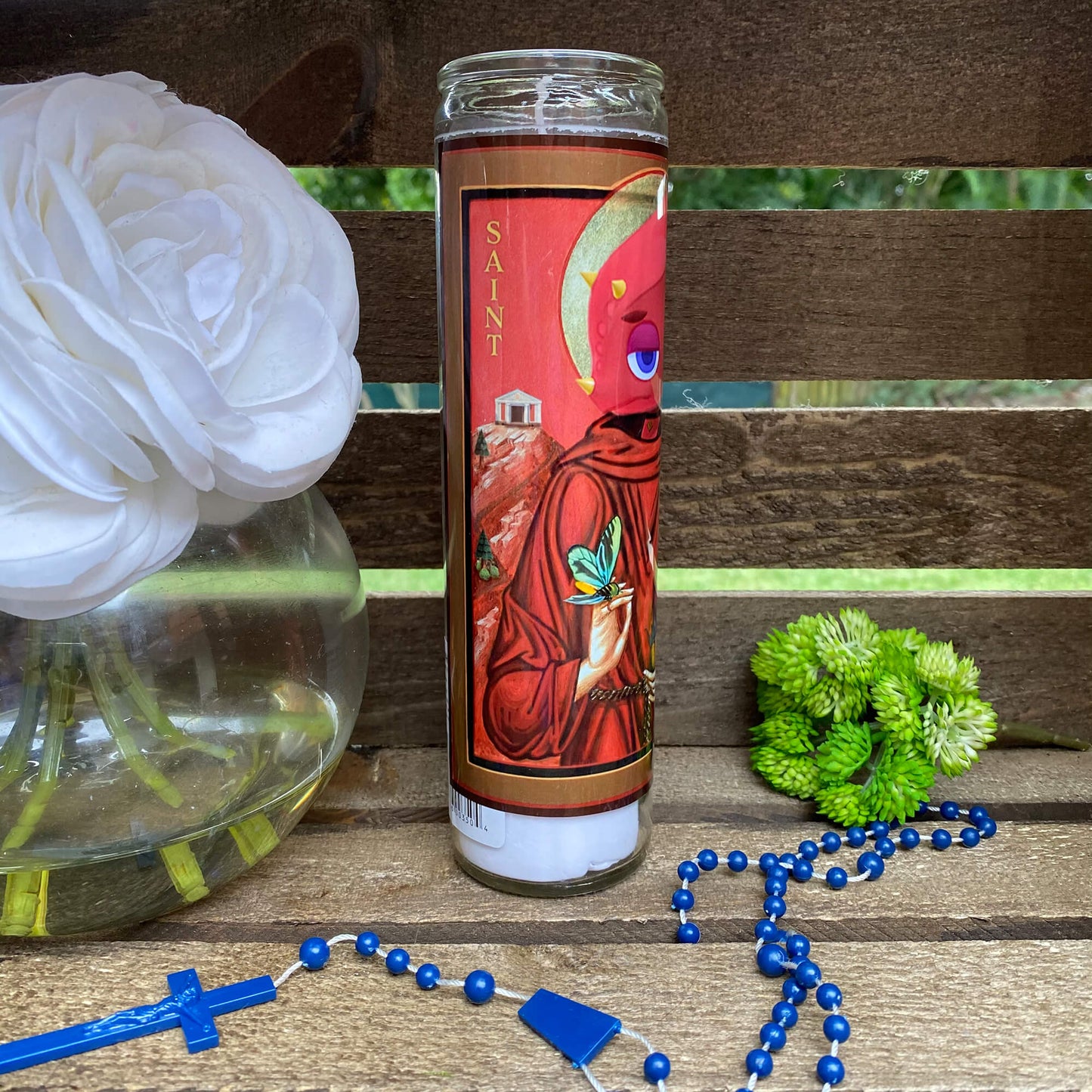 a glass of water sitting on a wooden bench next to a flower