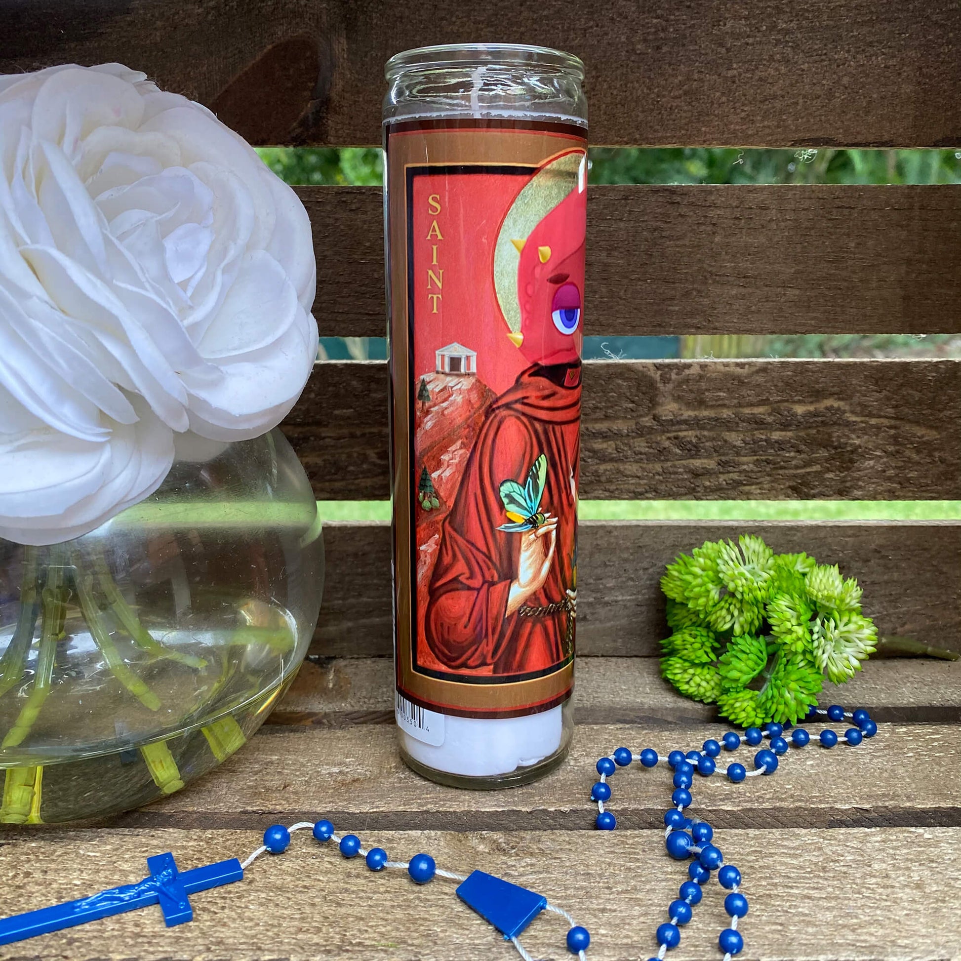 a glass of water sitting on a wooden bench next to a flower