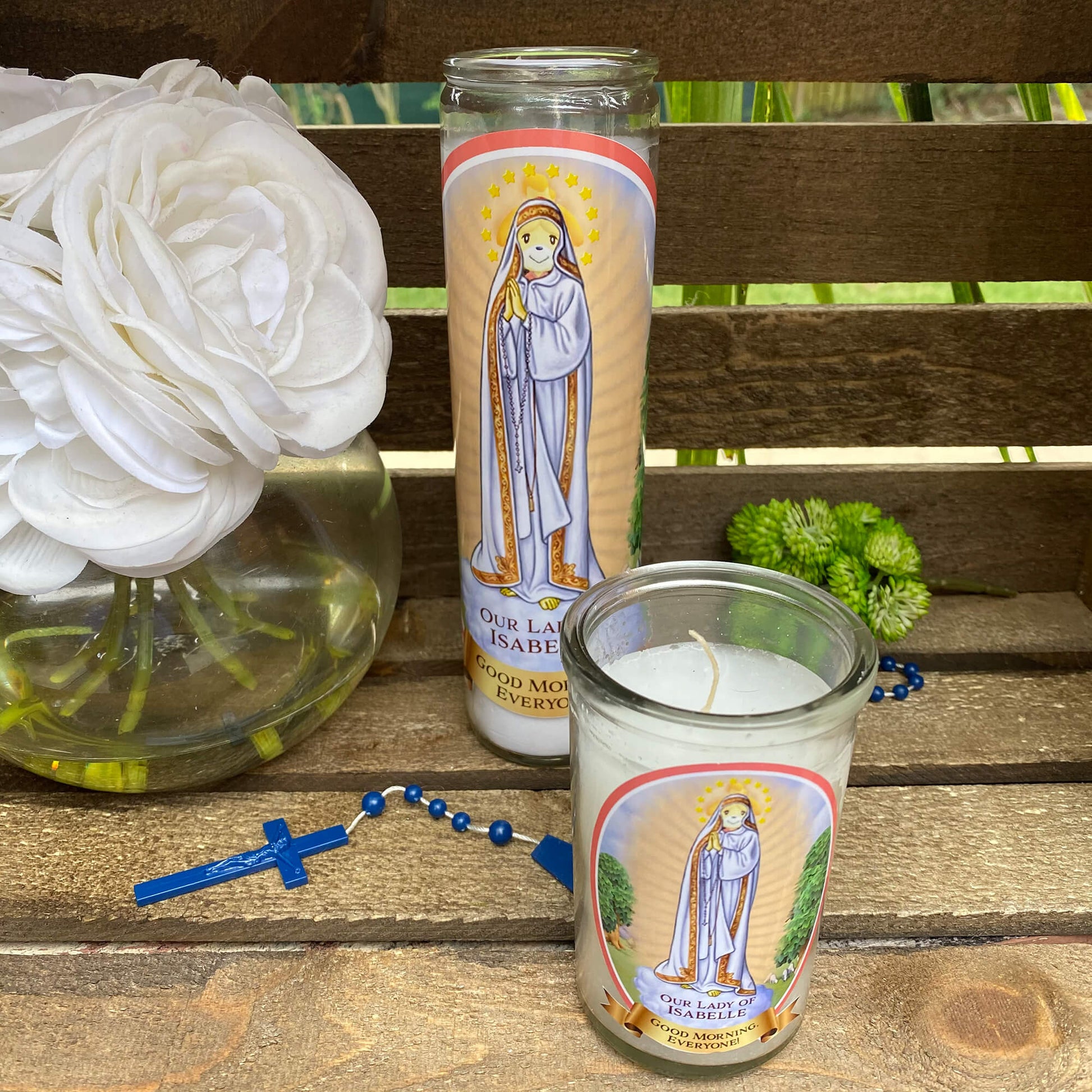 a candle and a vase with flowers on a bench