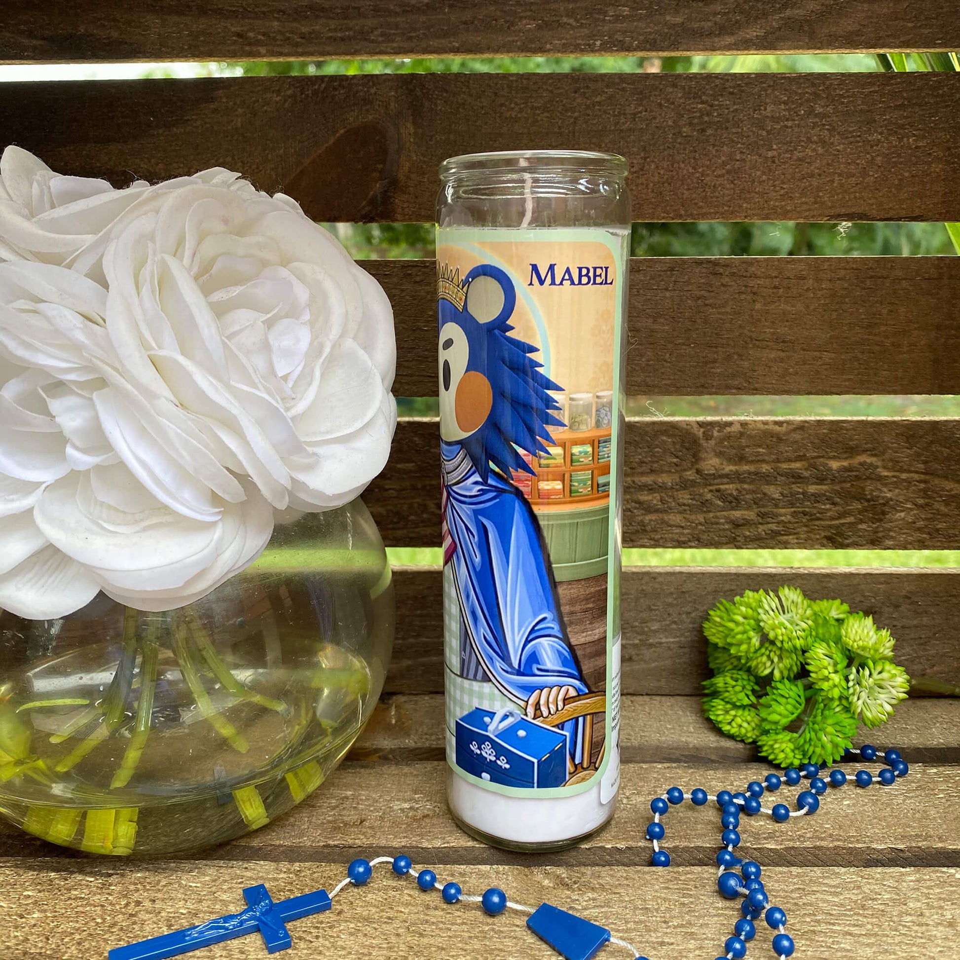 a vase of flowers and a rosary on a bench