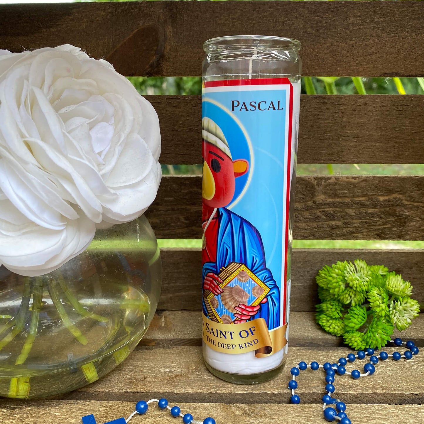 a rosary, a candle, and a flower on a bench