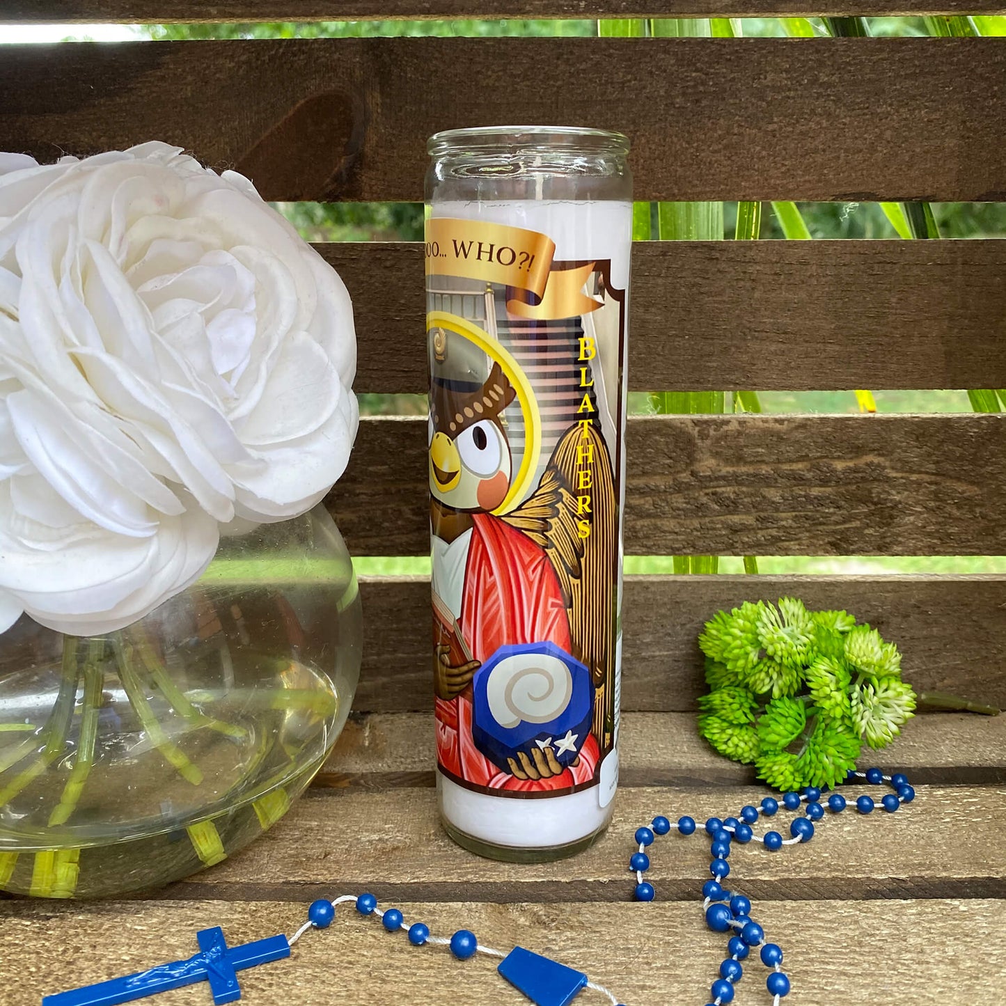 a white flower and a blue beaded necklace on a wooden bench